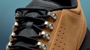 Close-up of a tan suede hiking boot with black laces threaded through silver metal eyelets.