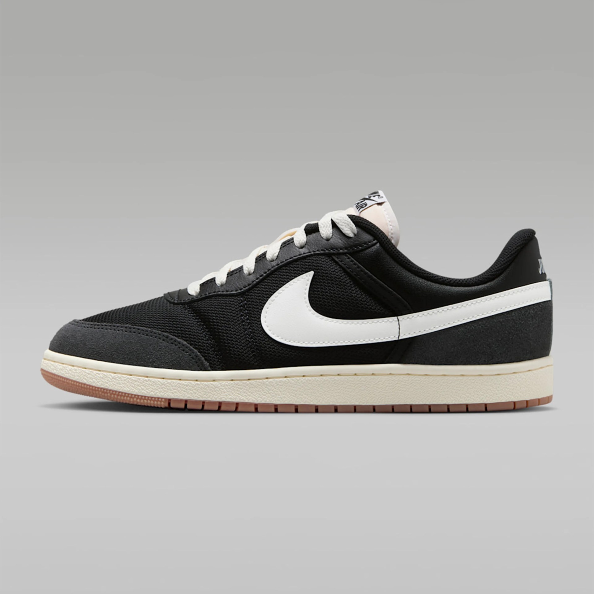 Black and dark gray low-top Nike sneaker with white swoosh logo and cream-colored sole.