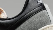 Close-up of a black and gray sneaker with textured suede and leather materials.