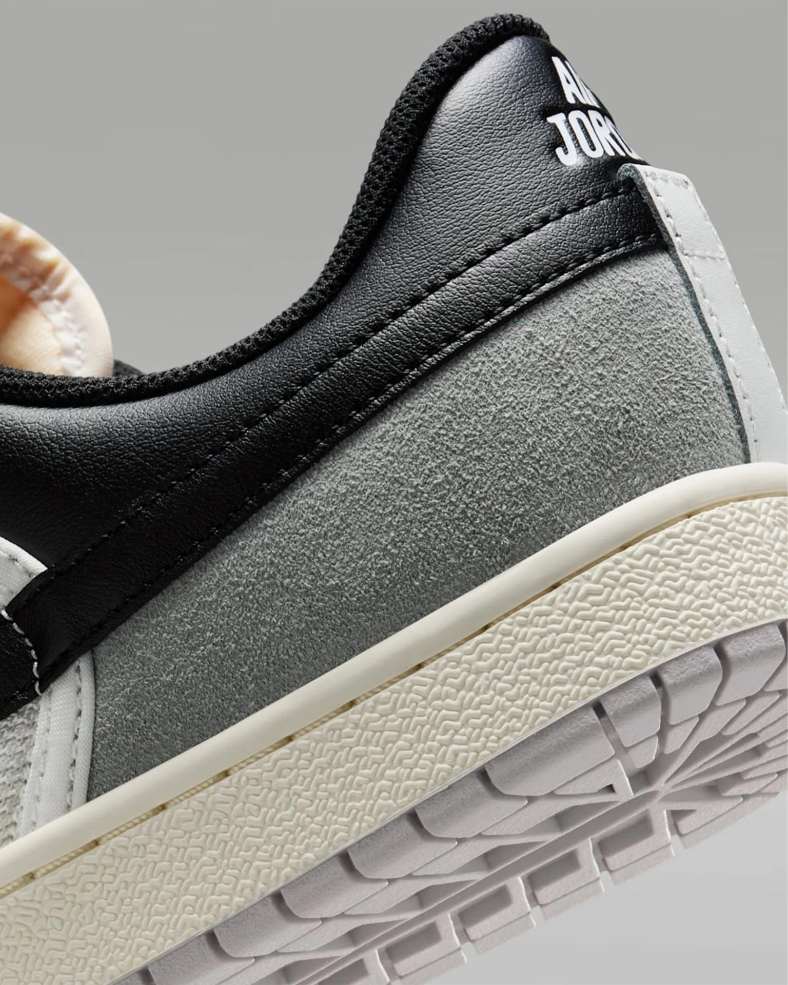 Close-up of a black, gray suede, and white Air Jordan sneaker heel with textured sole and "AIR JORDAN" text.