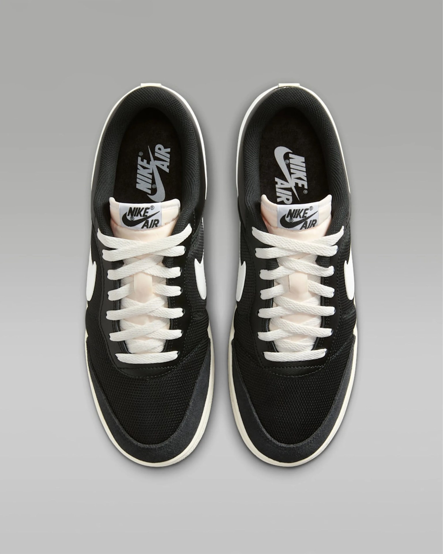 Pair of black and white Nike Air sneakers with white laces viewed from above on a gray background.