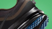 Close-up of a black and brown running shoe with blue tread and "INTERNATIONAL RUNNING TEAM" text on the sole.