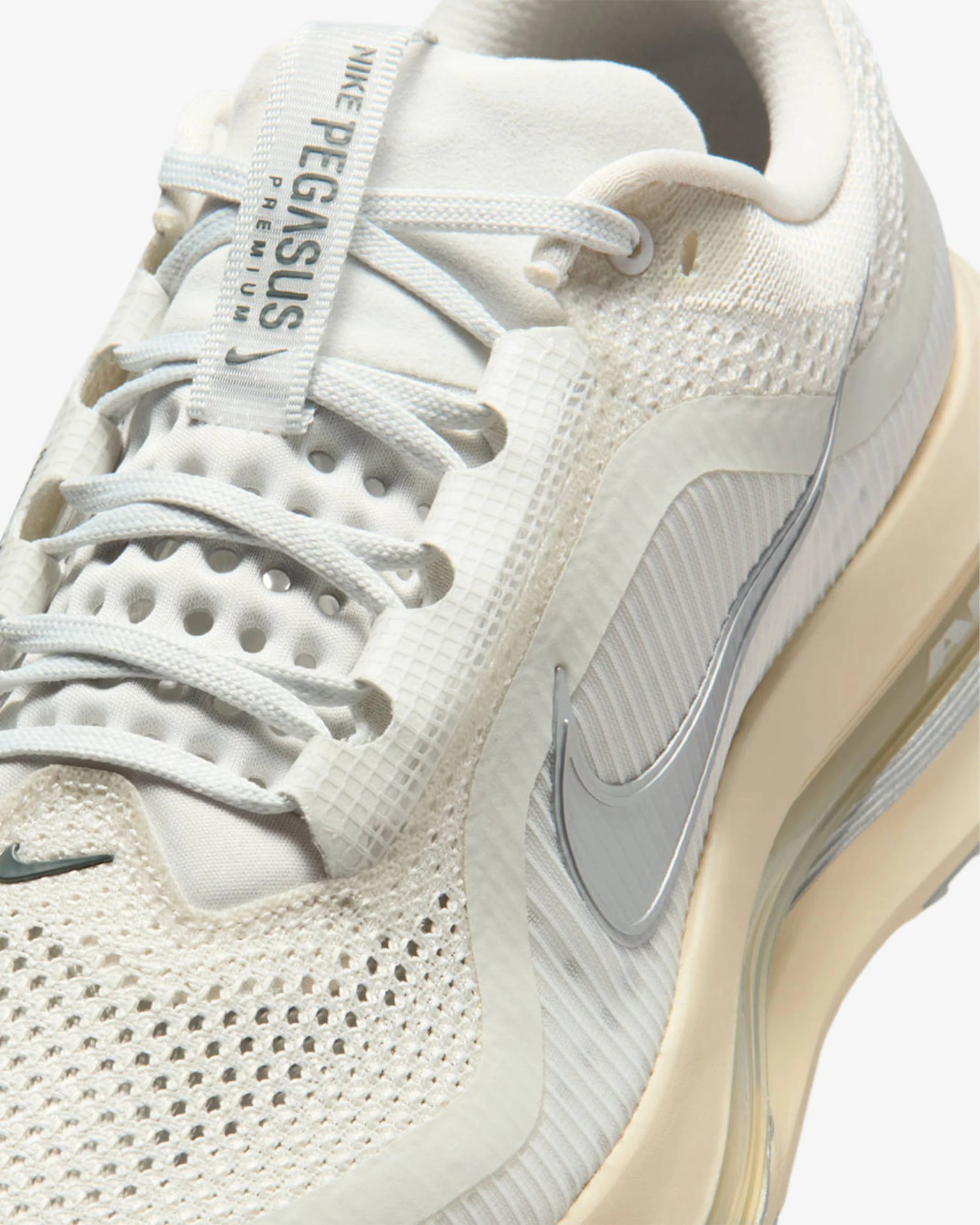Close-up of a white Nike Pegasus Premium sneaker with mesh upper, white laces, and beige sole with visible air cushion.
