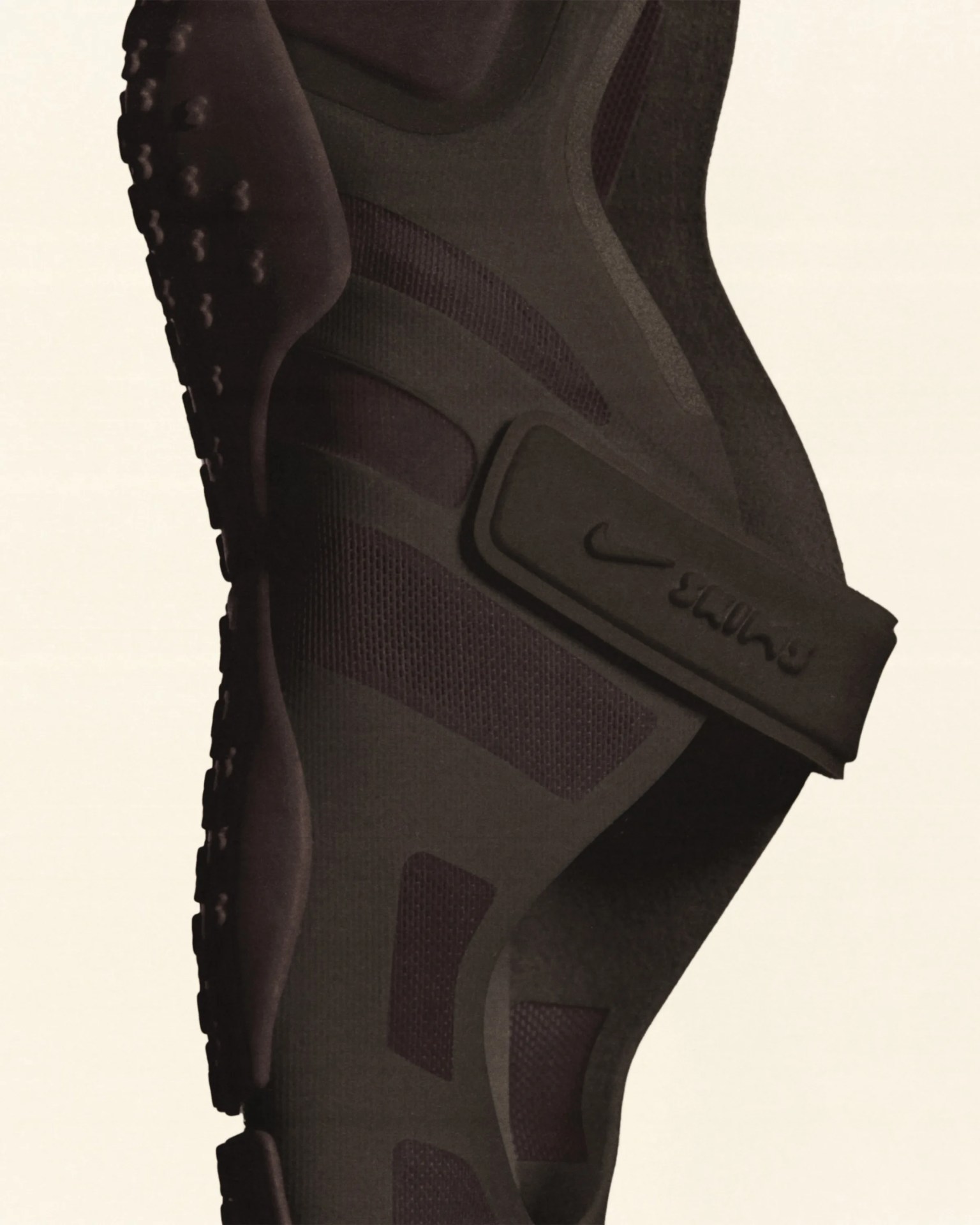 Close-up of a black Nike shoe with a textured sole and a strap featuring the Nike logo and "Stüssy" branding.