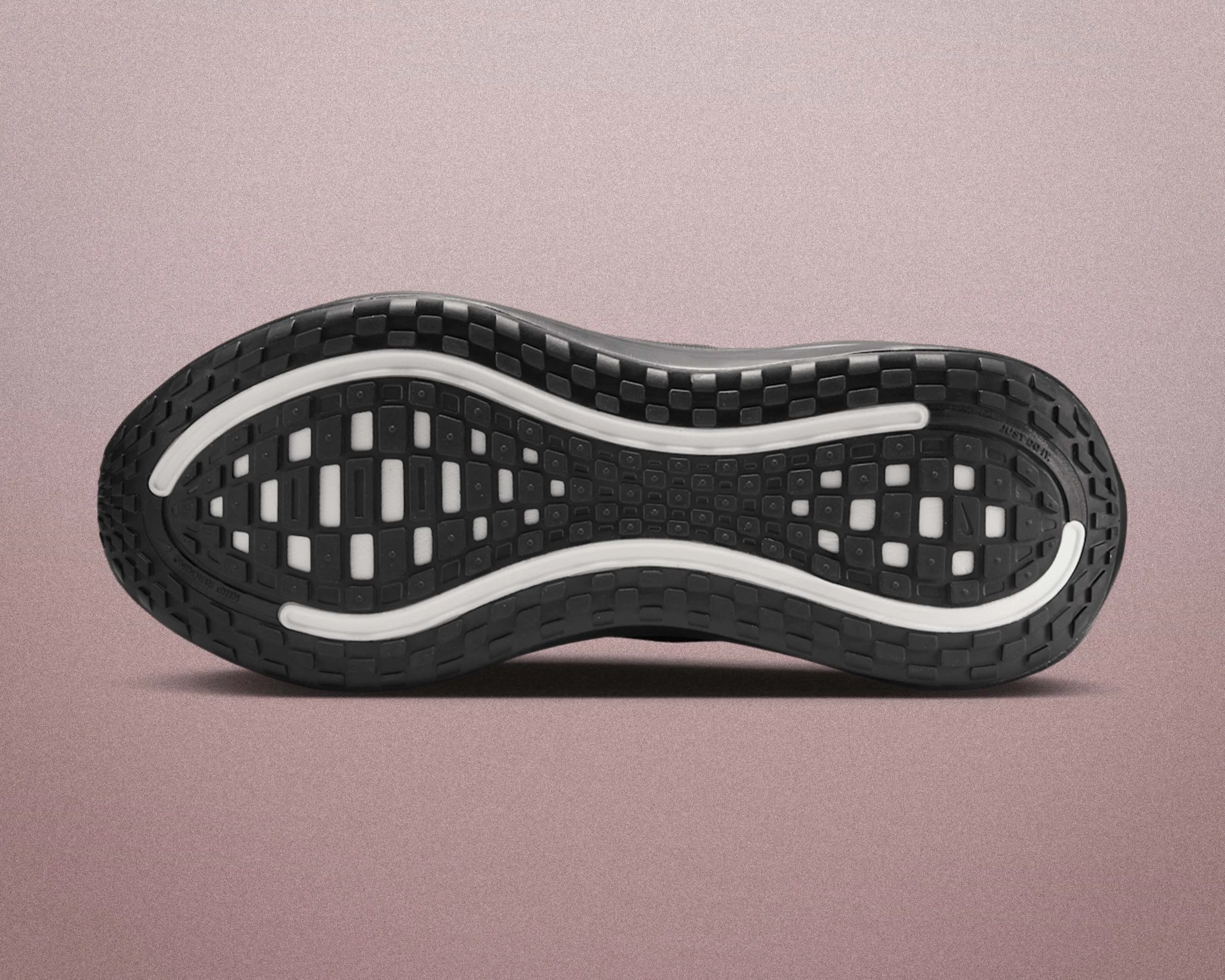 Black and white rubber shoe sole with a grid pattern and curved white lines on a pink surface.
