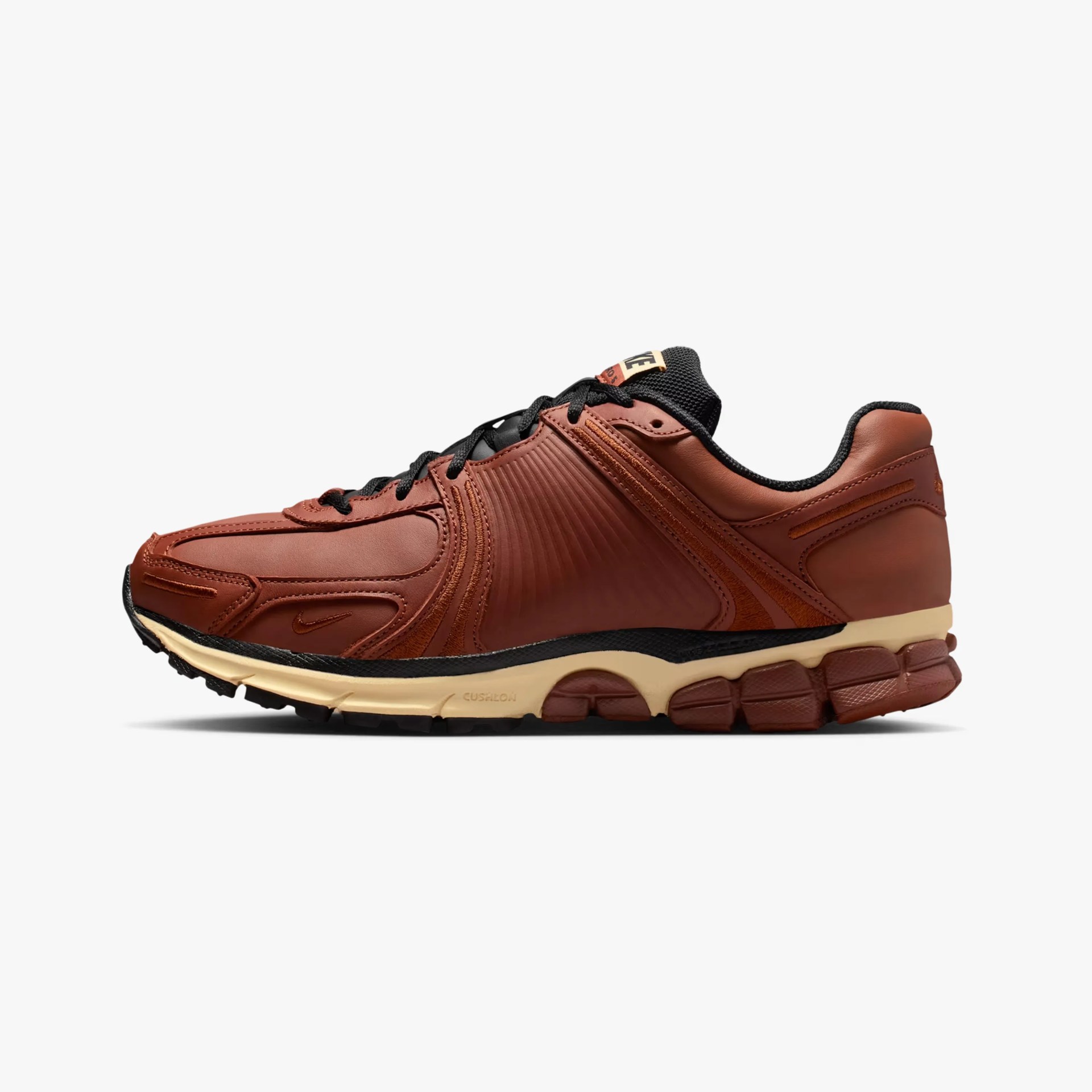 Brown leather Nike sneaker with black laces and beige cushioned sole shown from the side.