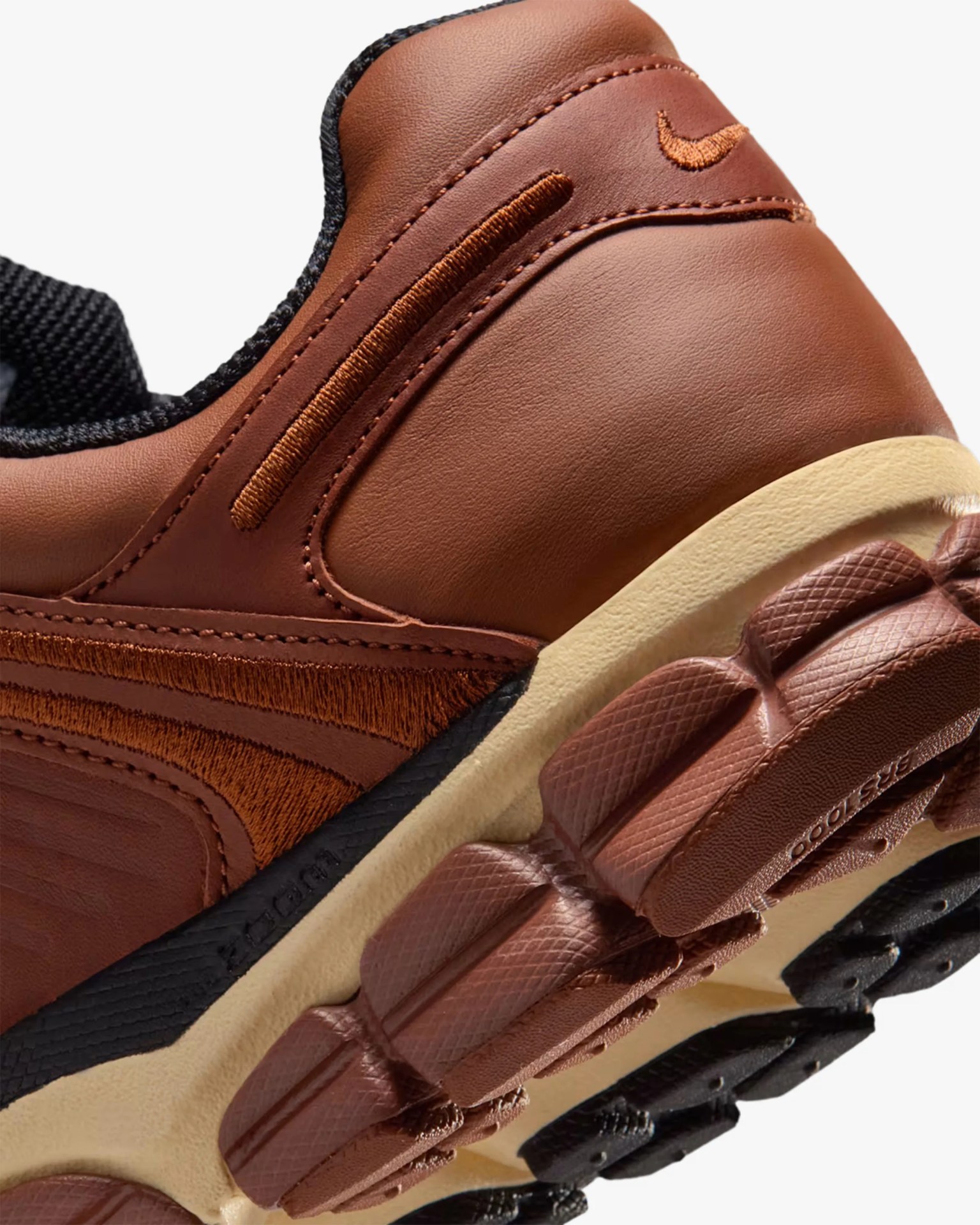 Close-up of a brown leather sneaker heel with textured brown and black sole and embroidered details.