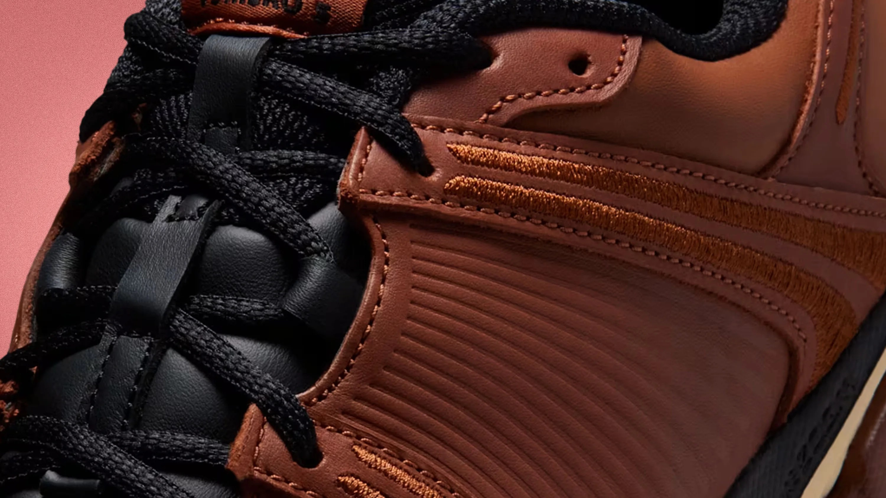 Close-up of a brown leather sneaker with black laces and textured side panel.