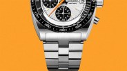 Close-up of a silver metal watch bracelet attached to a chronograph watch with a black and white dial and orange second hand.