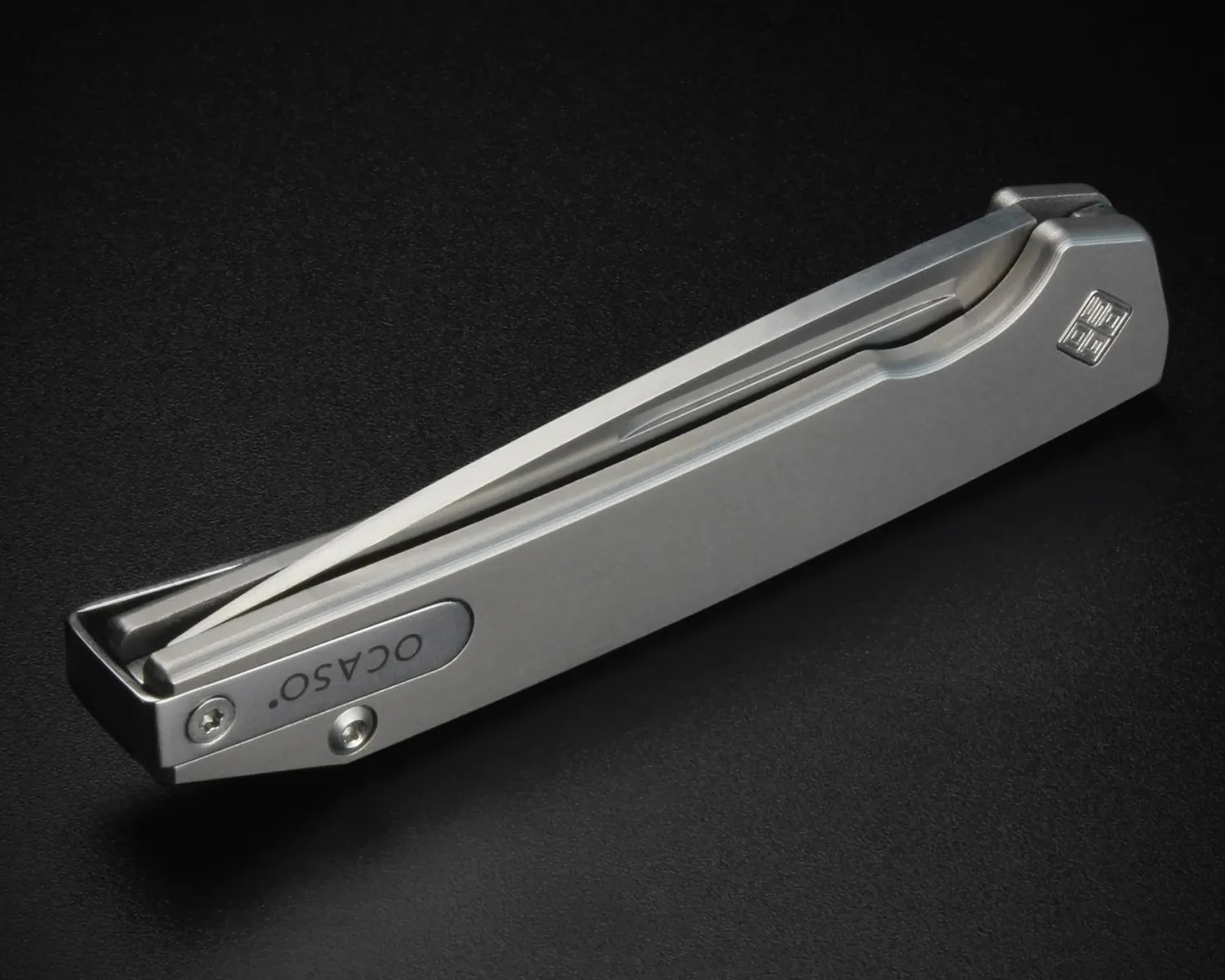Matte silver folding knife with a sleek, minimalist design and "OCASO" engraved on the handle.