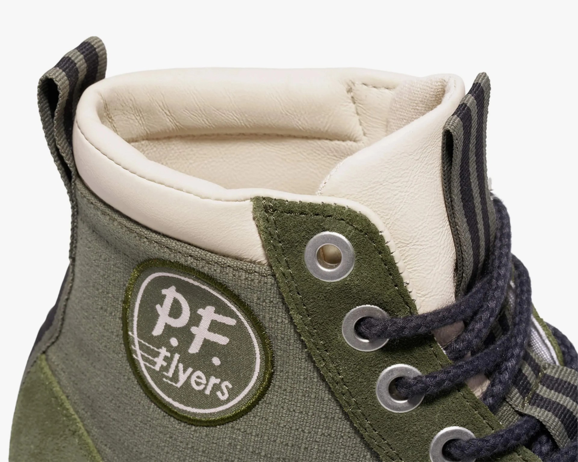 Close-up of an olive green PF Flyers high-top sneaker with cream padded collar and striped pull tabs.