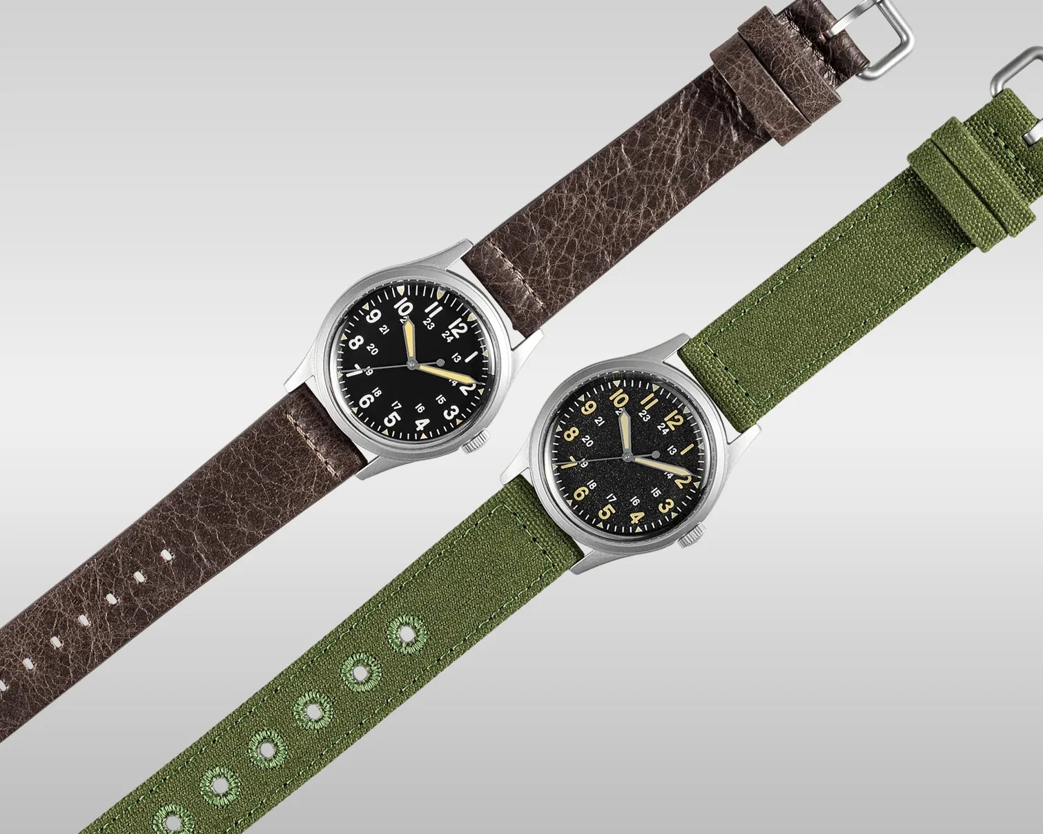Two wristwatches with black dials, one with a brown leather strap and the other with a green fabric strap, on a gray background.