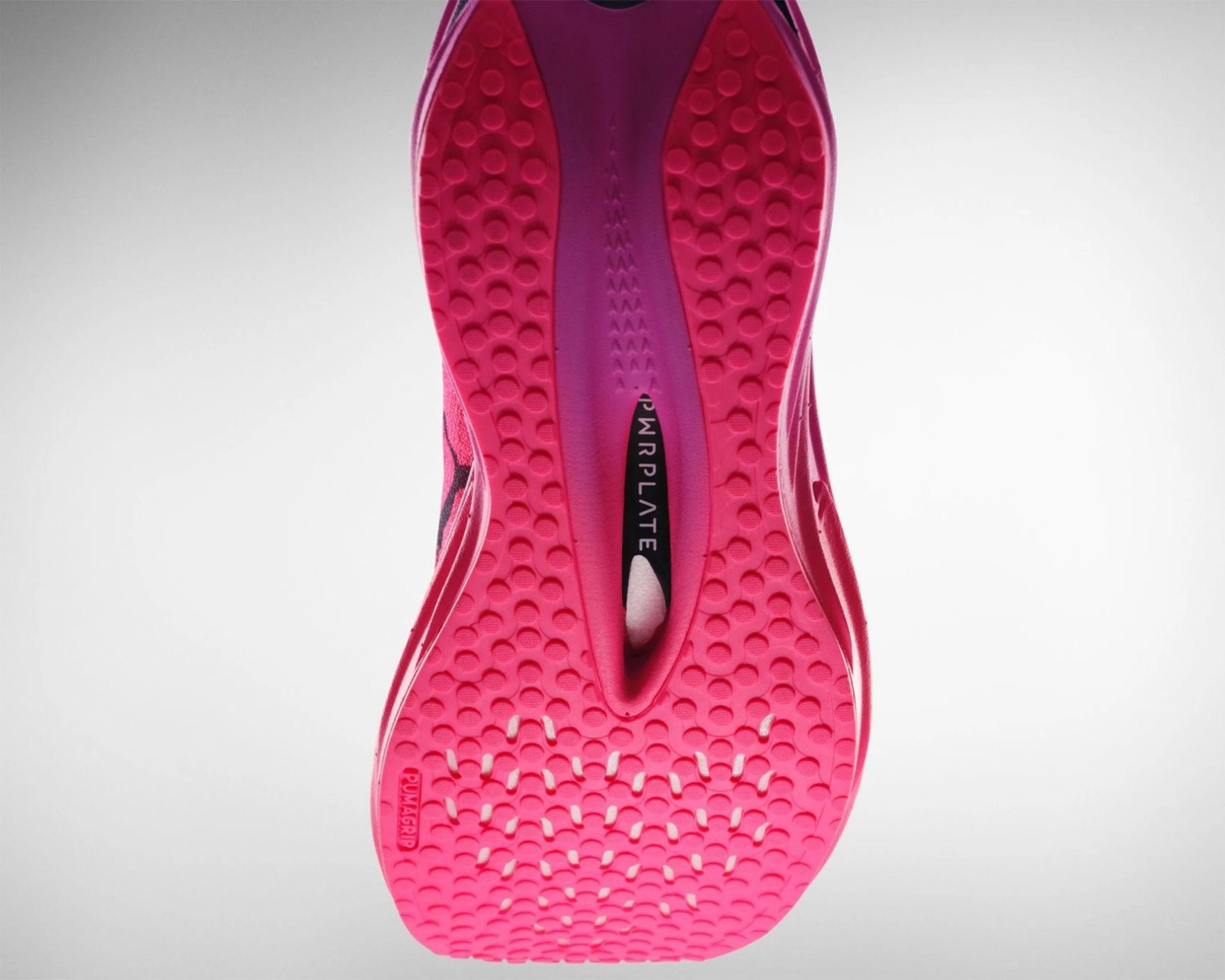 Bright pink running shoe sole with textured grip and "PWRPLATE" visible in the midfoot cutout.