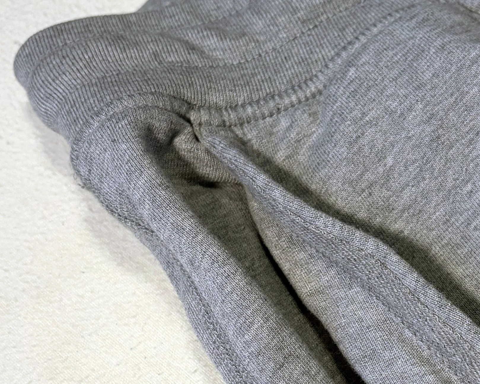Close-up of a gray ribbed knit fabric with visible seams and stitching.