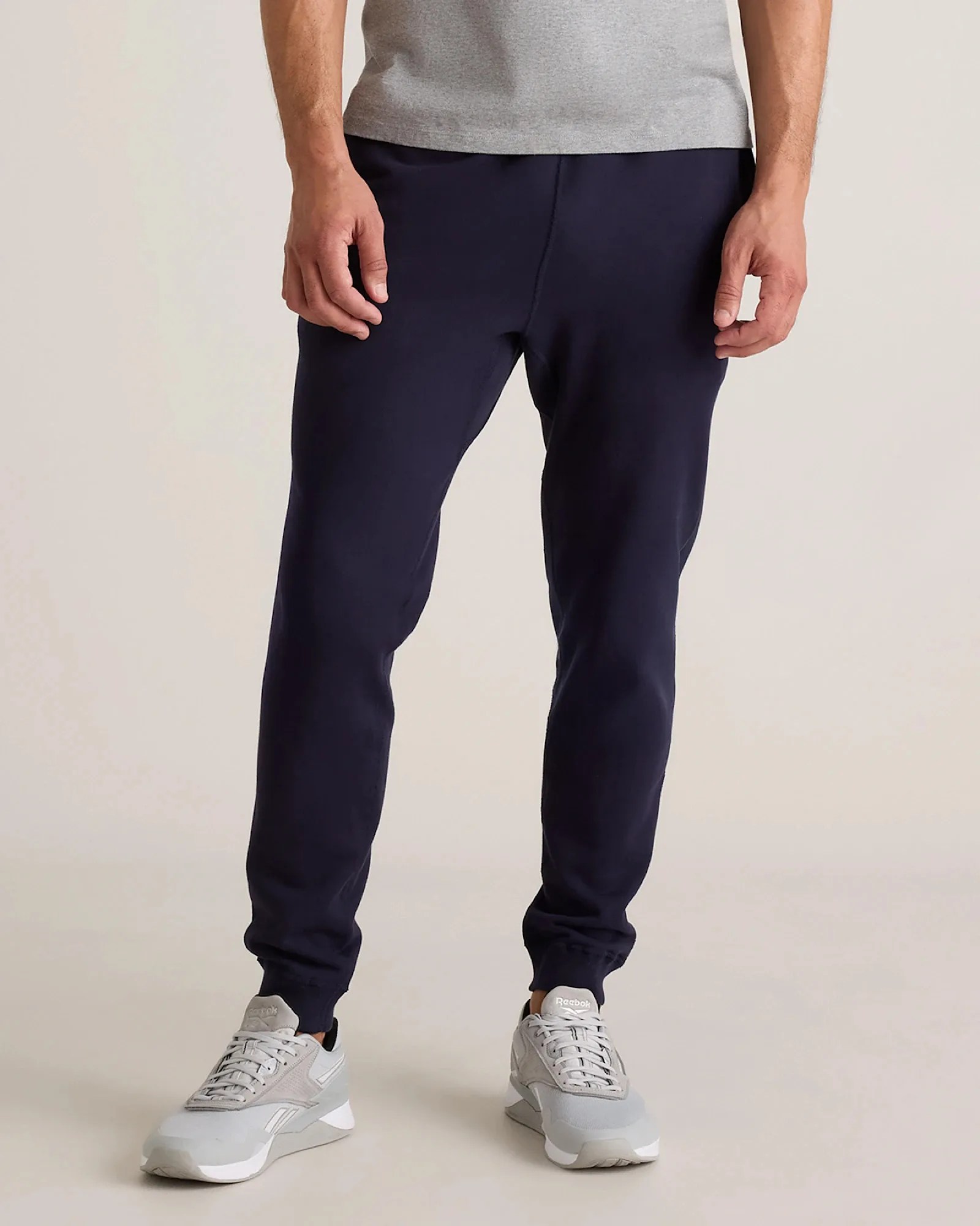 Navy blue jogger pants worn with light gray Reebok sneakers and a gray shirt.