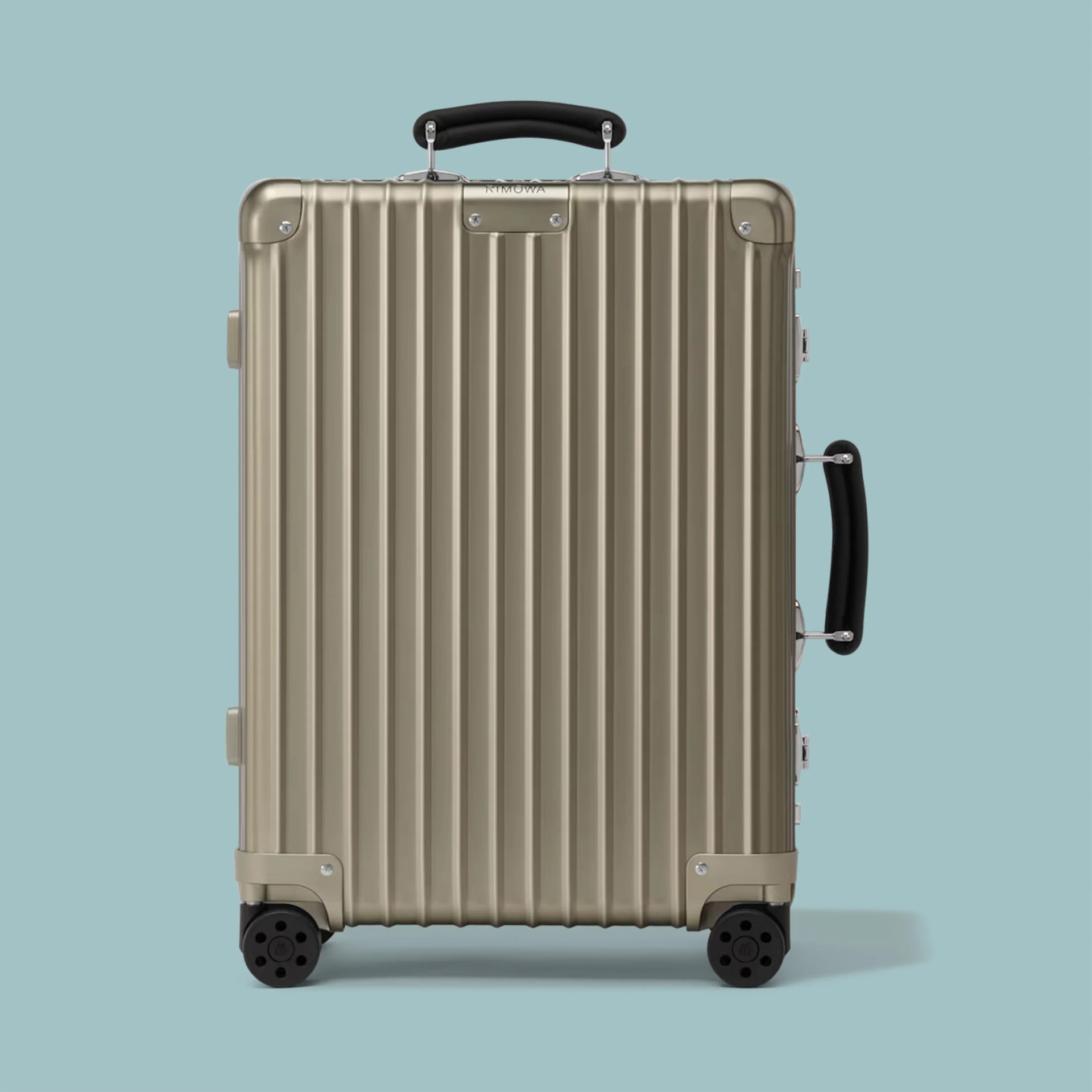 Metallic gold hard-shell suitcase with vertical ridges, black handles, and four black wheels on a blue background.