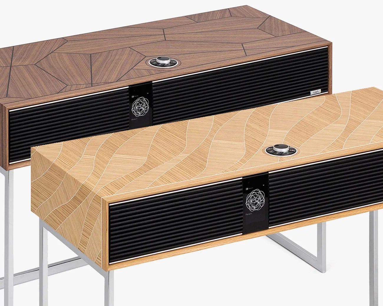 Two modern wooden speakers with black front grills and geometric patterns on top, one in dark wood and one in light wood, on metal stands.