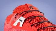 Close-up of a red athletic shoe with black laces and a white logo tab on the side.