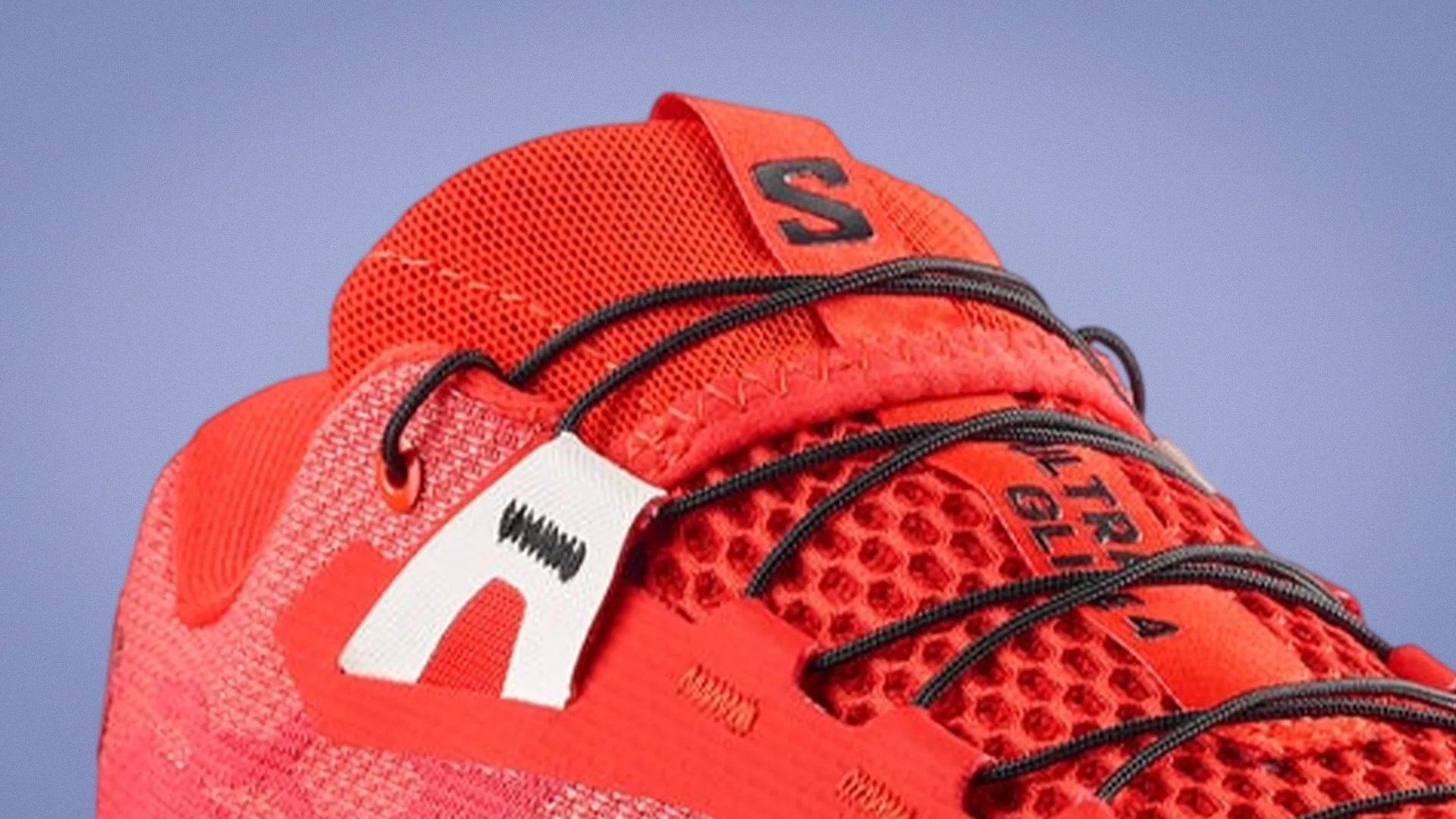 Close-up of a red athletic shoe with black laces and a white logo tab on the side.