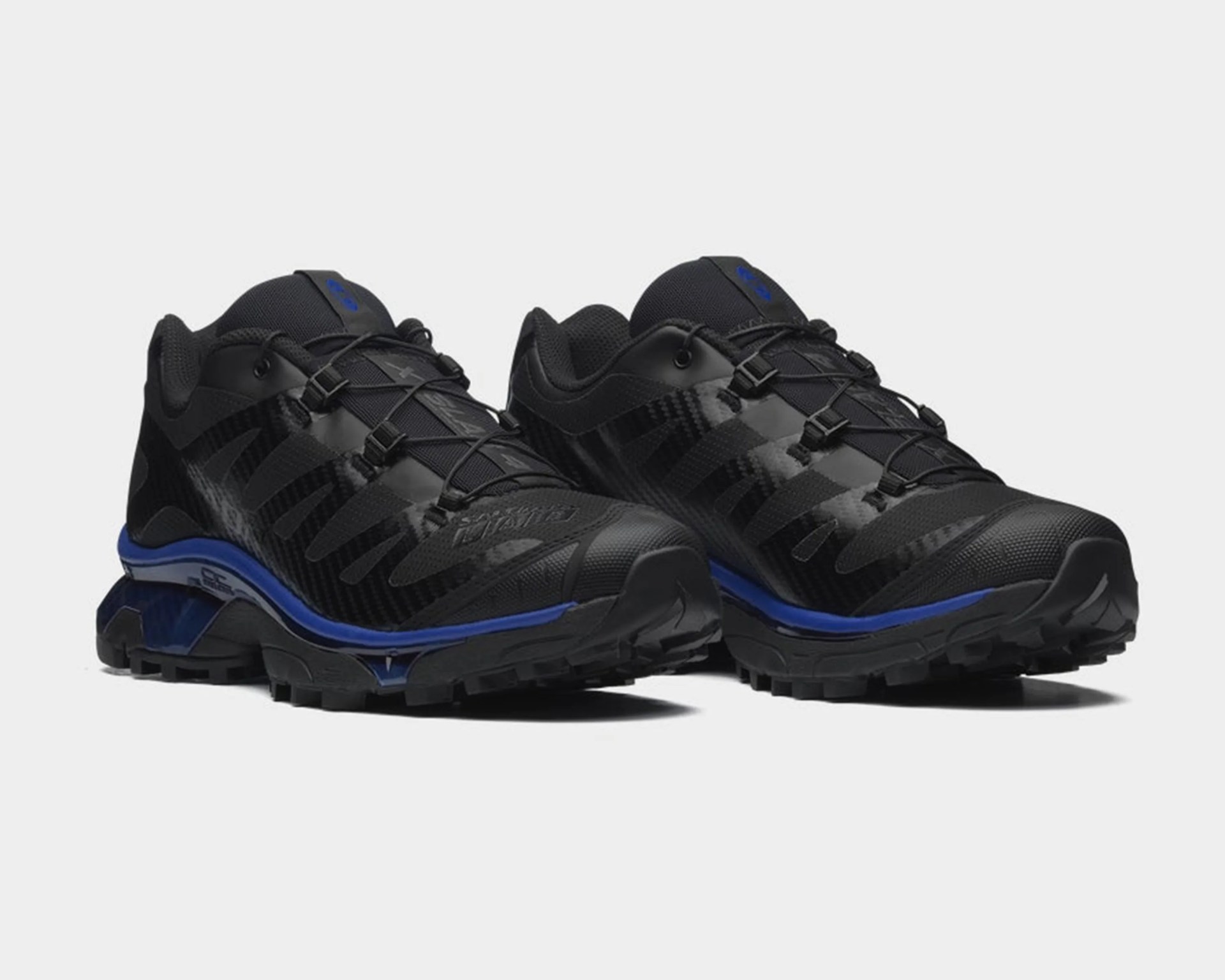 Pair of black and blue trail running shoes with textured soles and elastic lacing system.