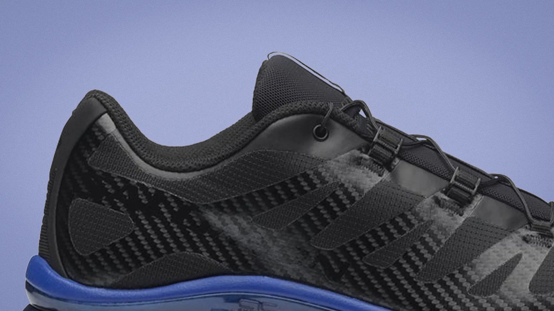 Close-up of a black athletic shoe with mesh and synthetic overlays and a blue midsole against a light purple background.