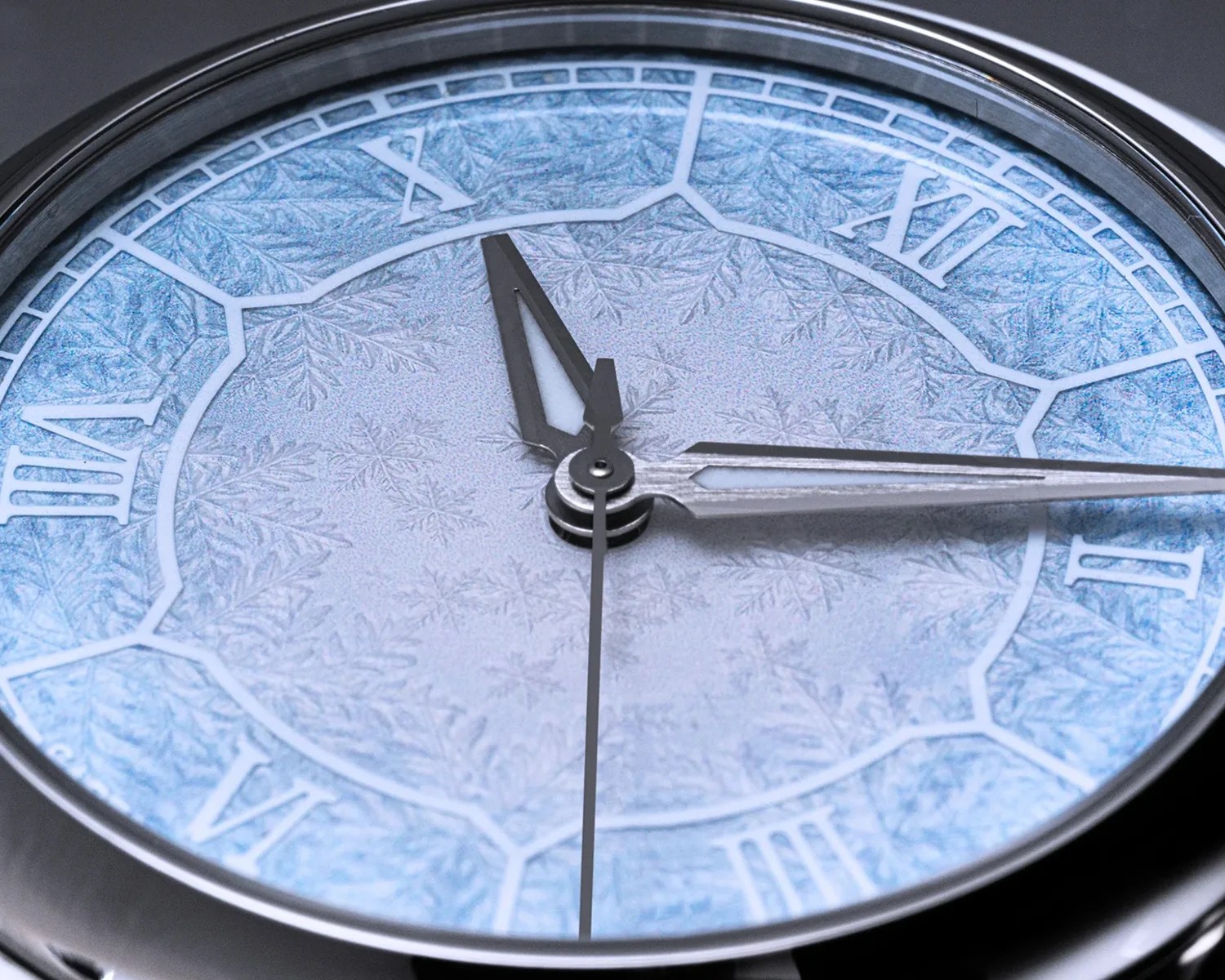 Close-up of a silver watch face with blue snowflake patterns and Roman numerals.