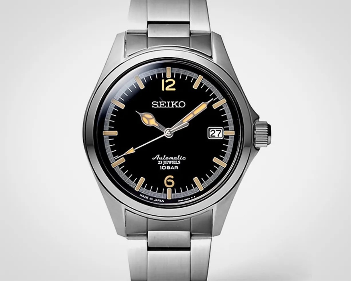 Silver stainless steel Seiko wristwatch with black dial, beige markers, and date display at 3 o'clock.