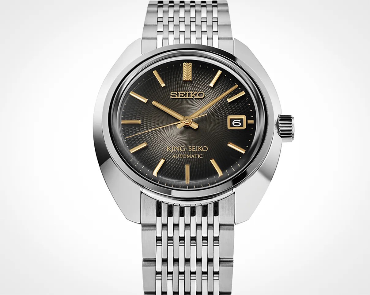 Silver stainless steel Seiko wristwatch with black textured dial and gold-tone hour markers and hands.