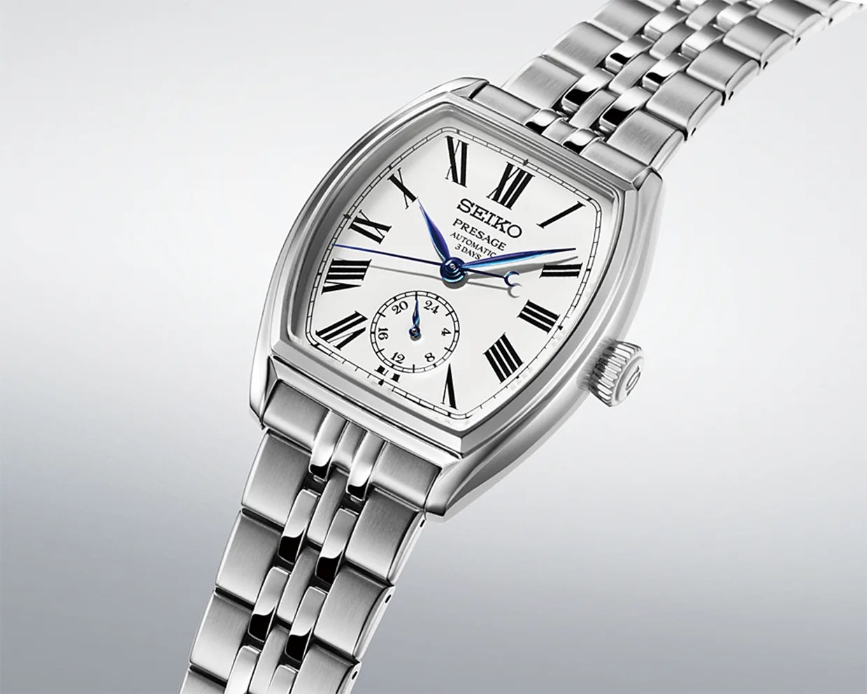 Silver Seiko Presage automatic wristwatch with white dial, black Roman numerals, blue hands, and stainless steel bracelet.