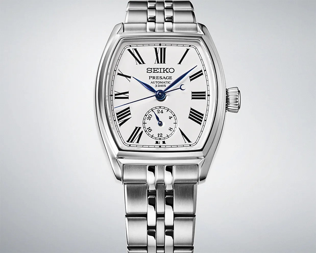 Silver Seiko Presage automatic wristwatch with white dial, black Roman numerals, blue hands, and metal link bracelet.