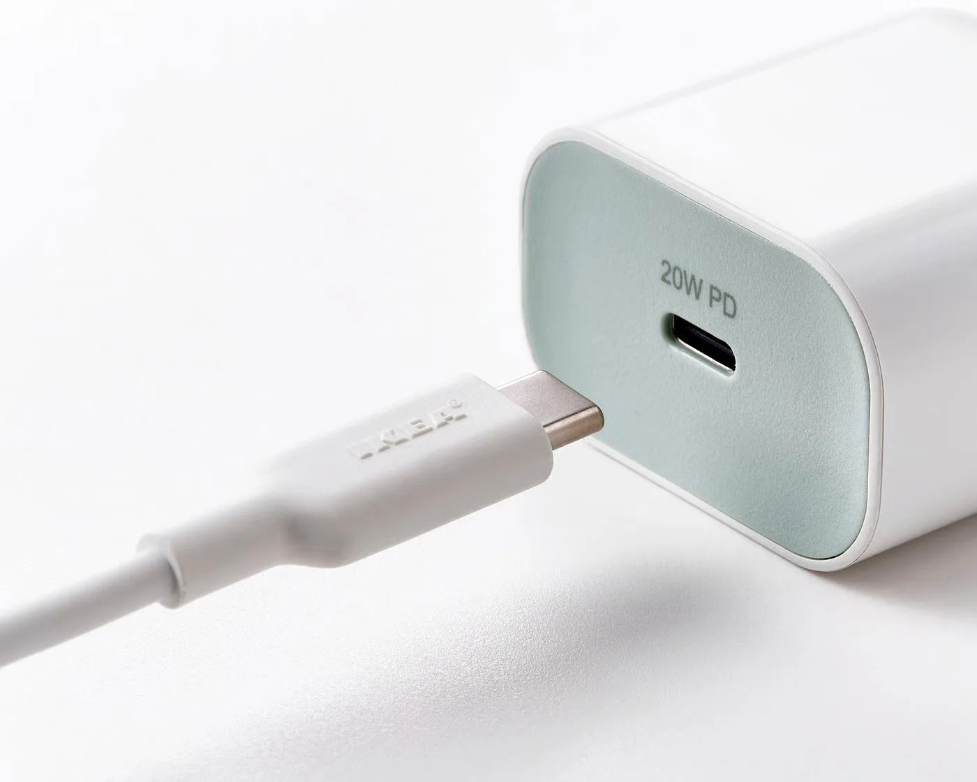White USB-C cable partially plugged into a white 20W PD USB-C power adapter on a white surface.