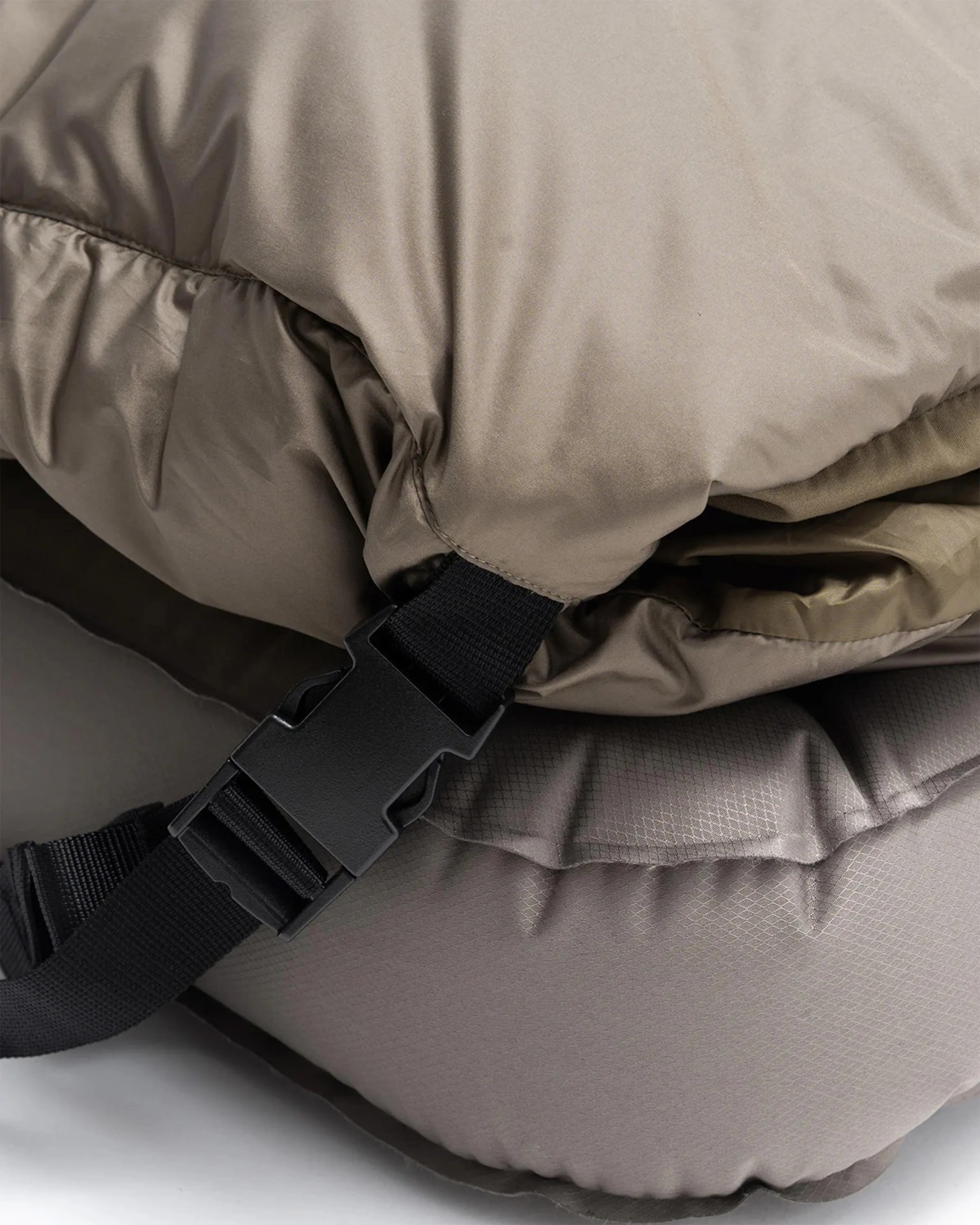 Close-up of a taupe padded fabric with a black plastic buckle and strap.