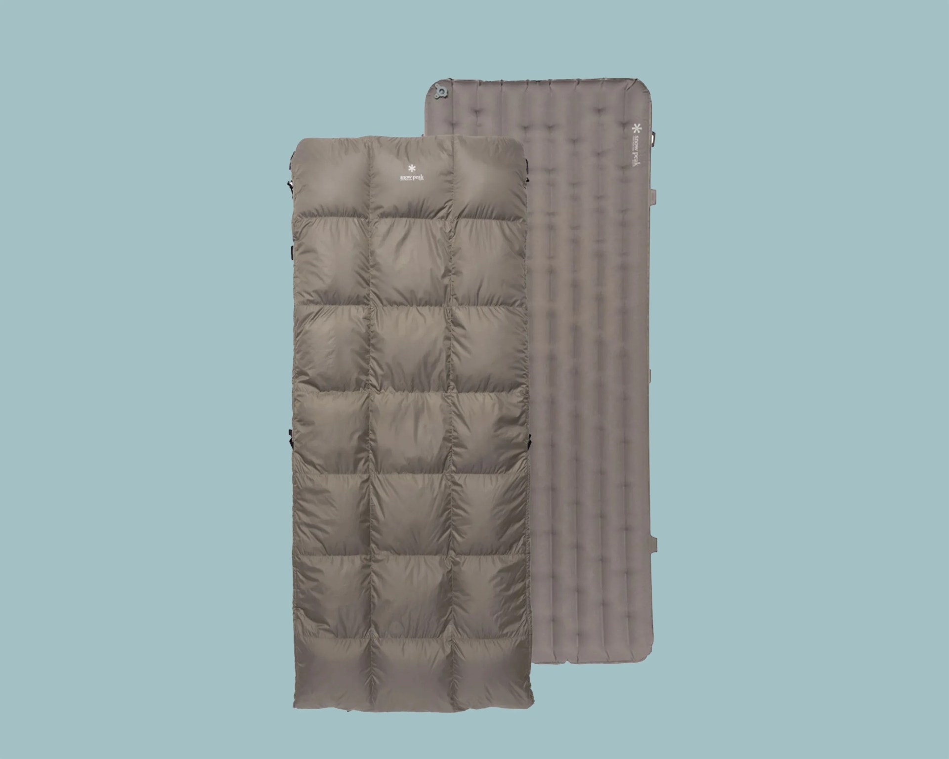 Two taupe-colored sleeping pads, one quilted and one inflatable, laid flat on a light blue background.