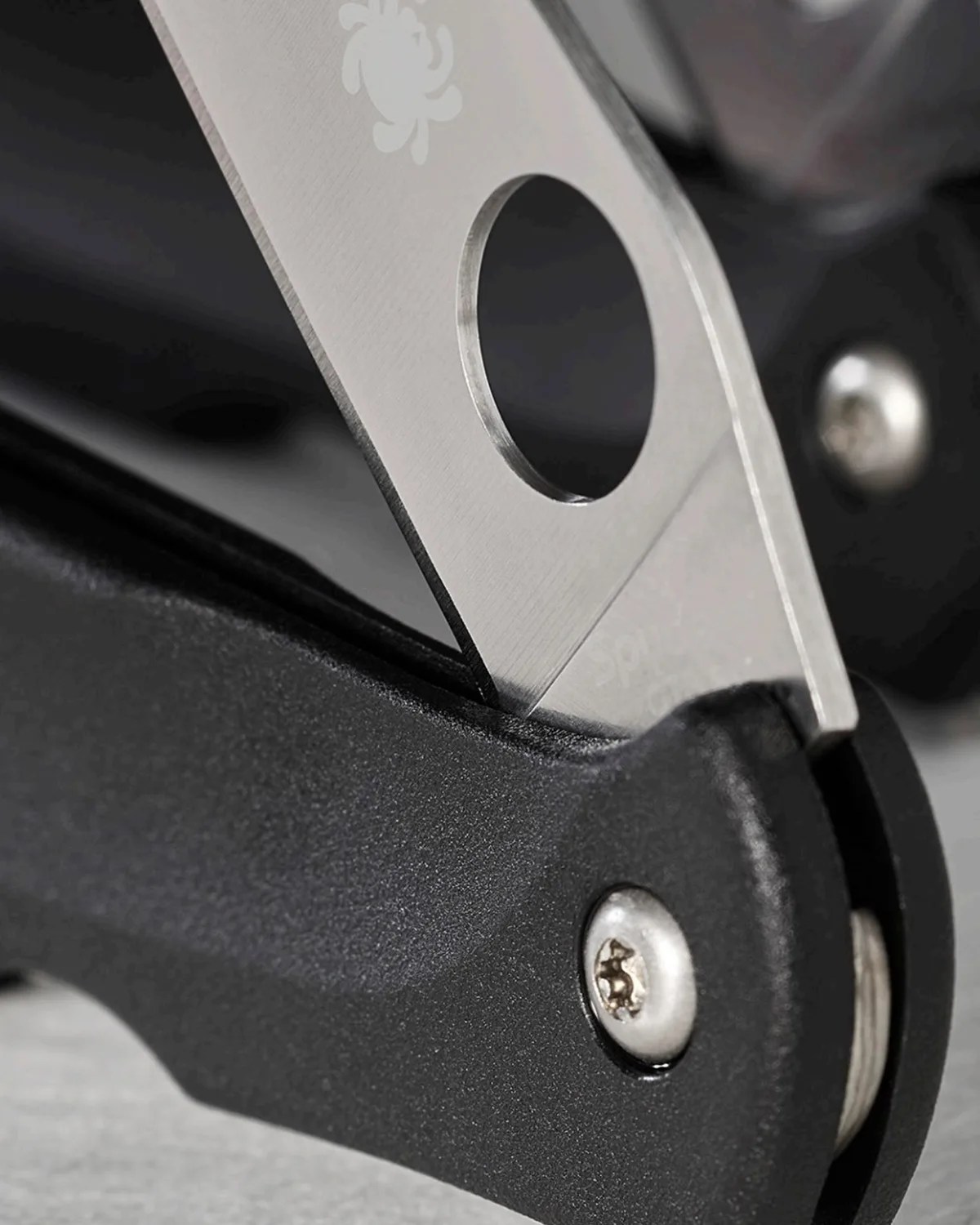 Close-up of a partially opened folding knife with a stainless steel blade and black textured handle.