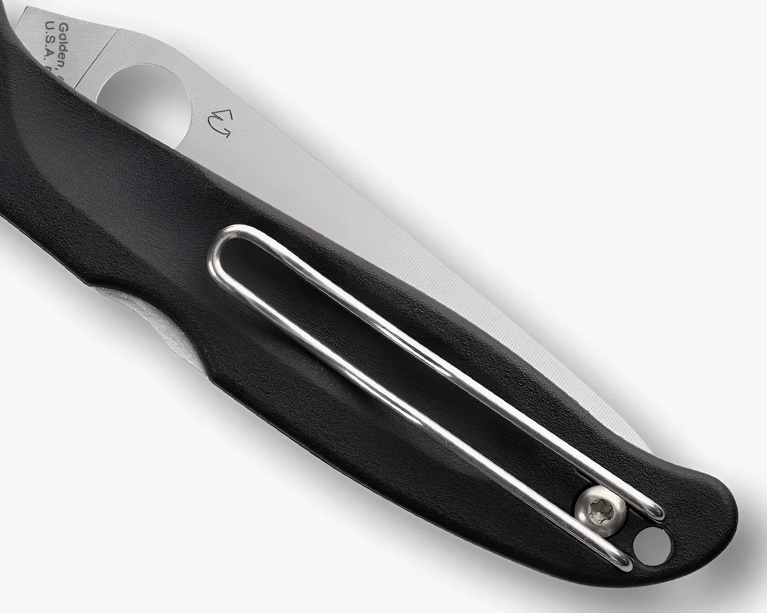 Close-up of a folding knife with a black textured handle and a silver metal clip attached.