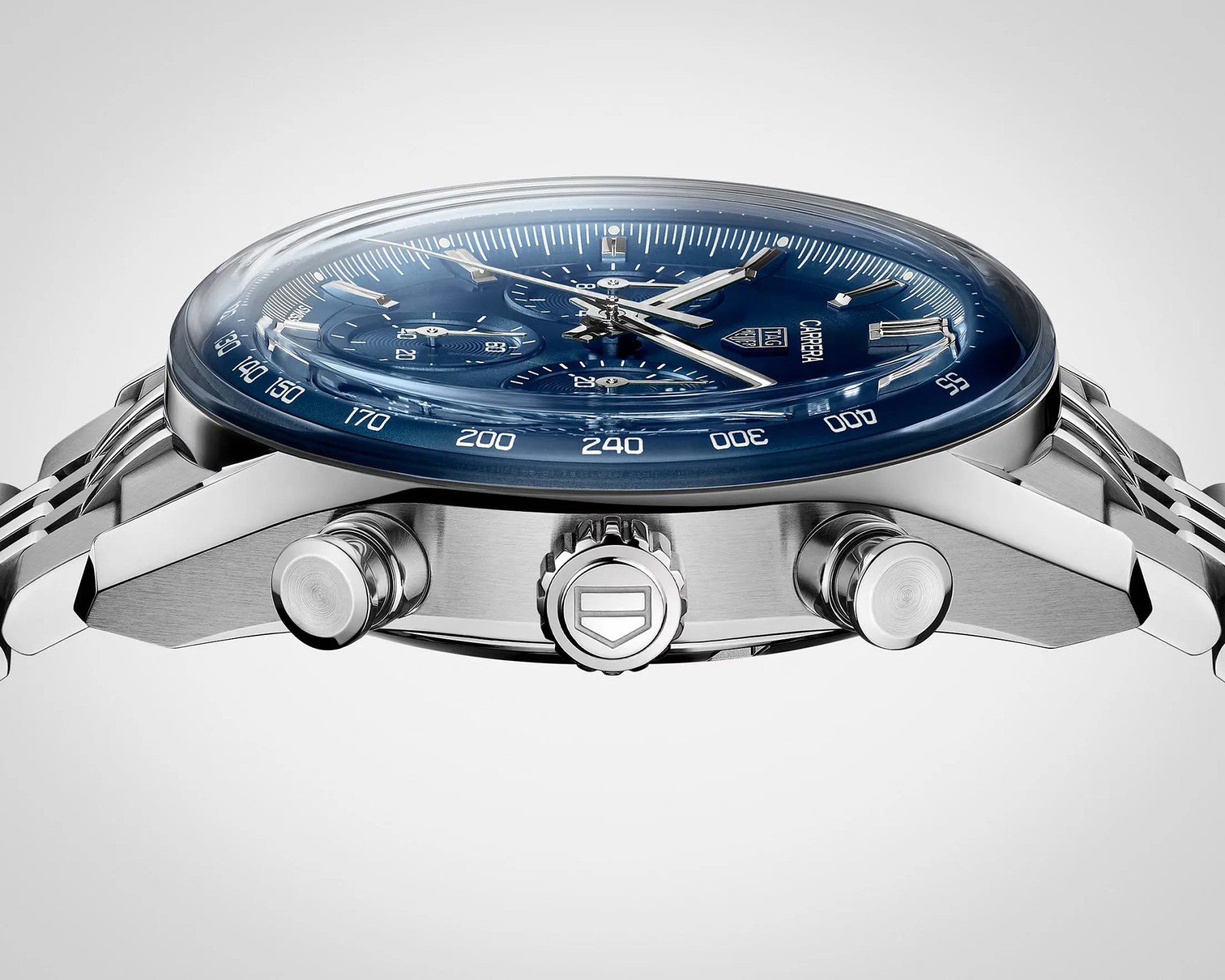 Silver TAG Heuer Carrera chronograph watch with a blue dial and tachymeter scale on a metal bracelet, side view.