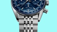 Close-up of a stainless steel watch bracelet attached to a blue chronograph watch face with silver markers and pushers.