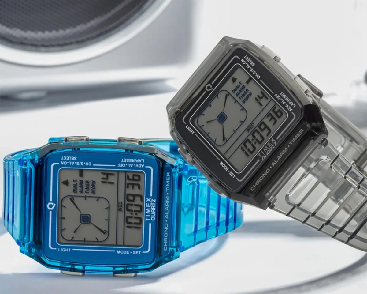Two Timex digital watches with translucent plastic bands, one in blue and one in clear gray, showing time and date.