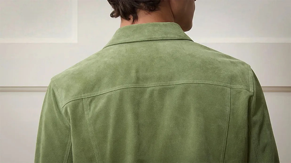 Back view of a person wearing a light green suede jacket with a collar.