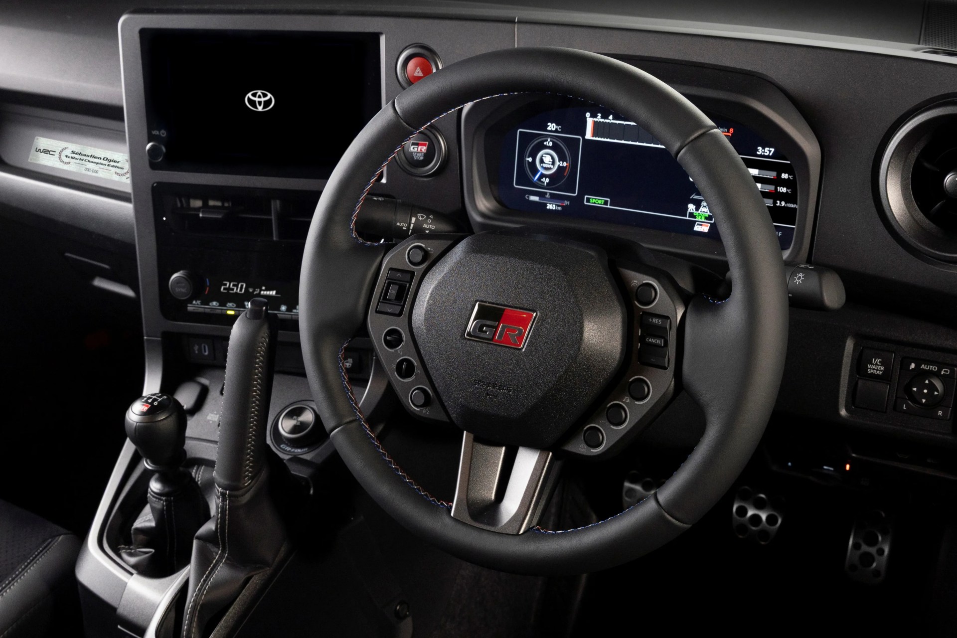 Black leather steering wheel with GR logo and multi-function buttons inside a Toyota car cockpit.