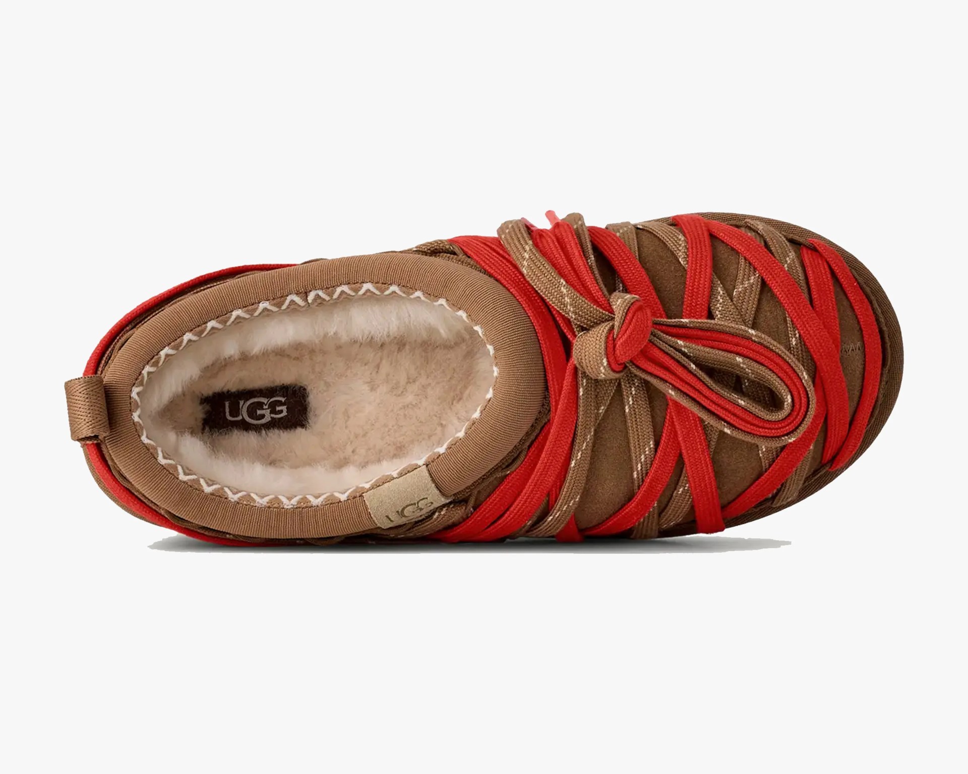 Top view of a brown UGG slipper with red crisscross straps and a fluffy cream interior lining.