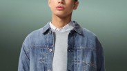 Person wearing a light blue denim jacket over a gray sweatshirt and a white collared shirt.