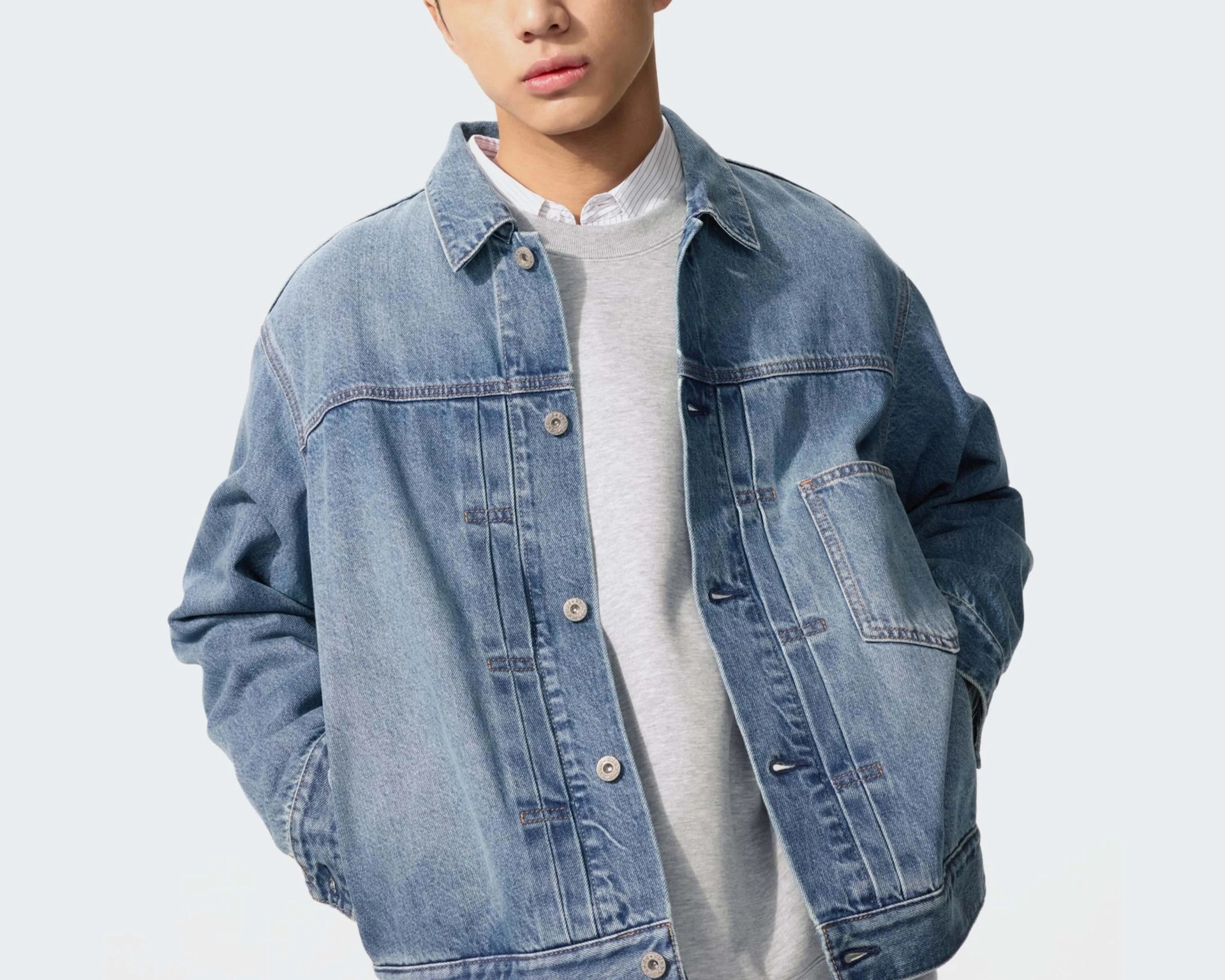Light blue oversized denim jacket with button closures worn over a gray sweatshirt and white collared shirt.