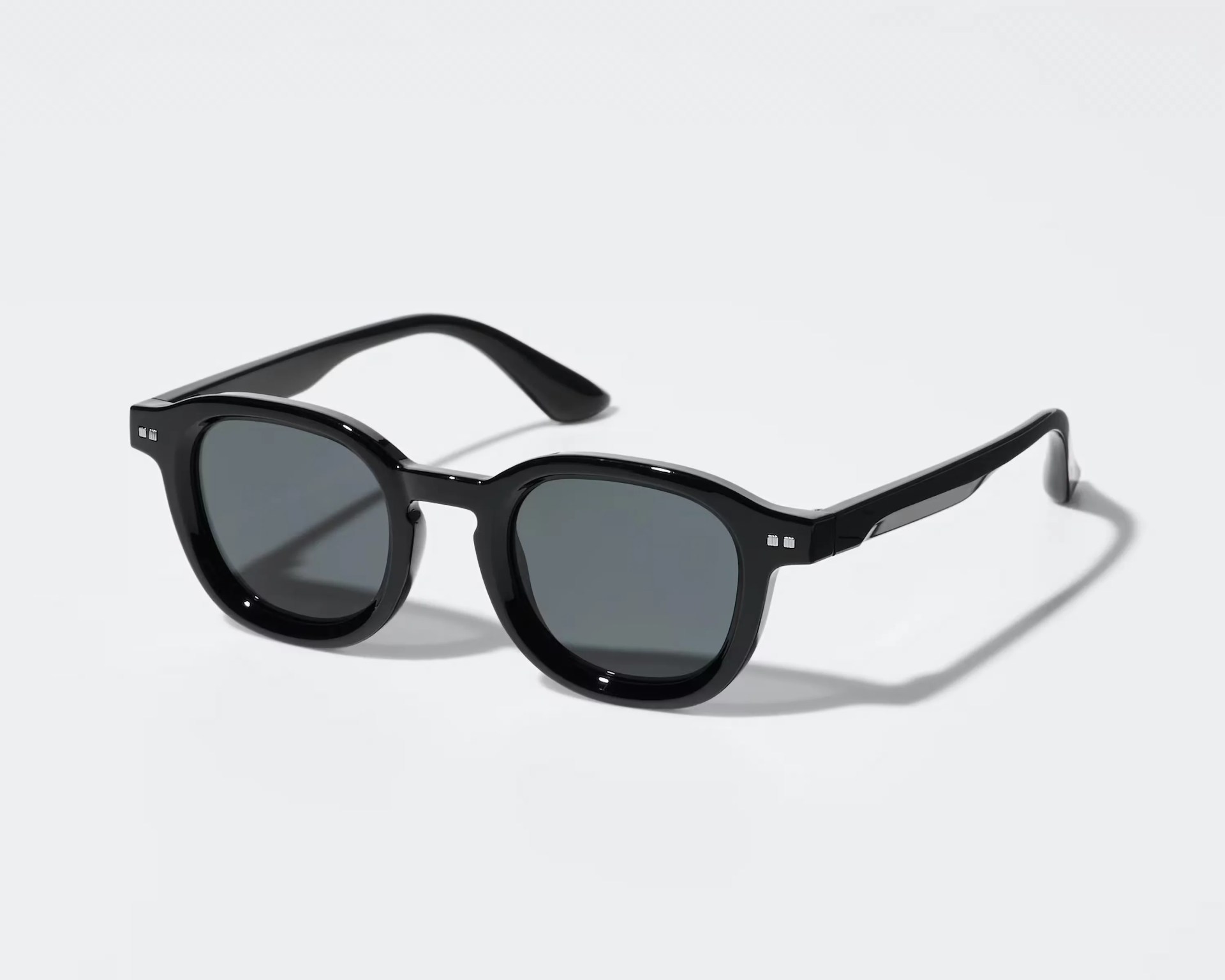Black acetate sunglasses with rounded square dark lenses and silver rivet details on the front corners.