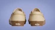 Pair of beige Vans sneakers with brown soles shown from the back against a purple background.