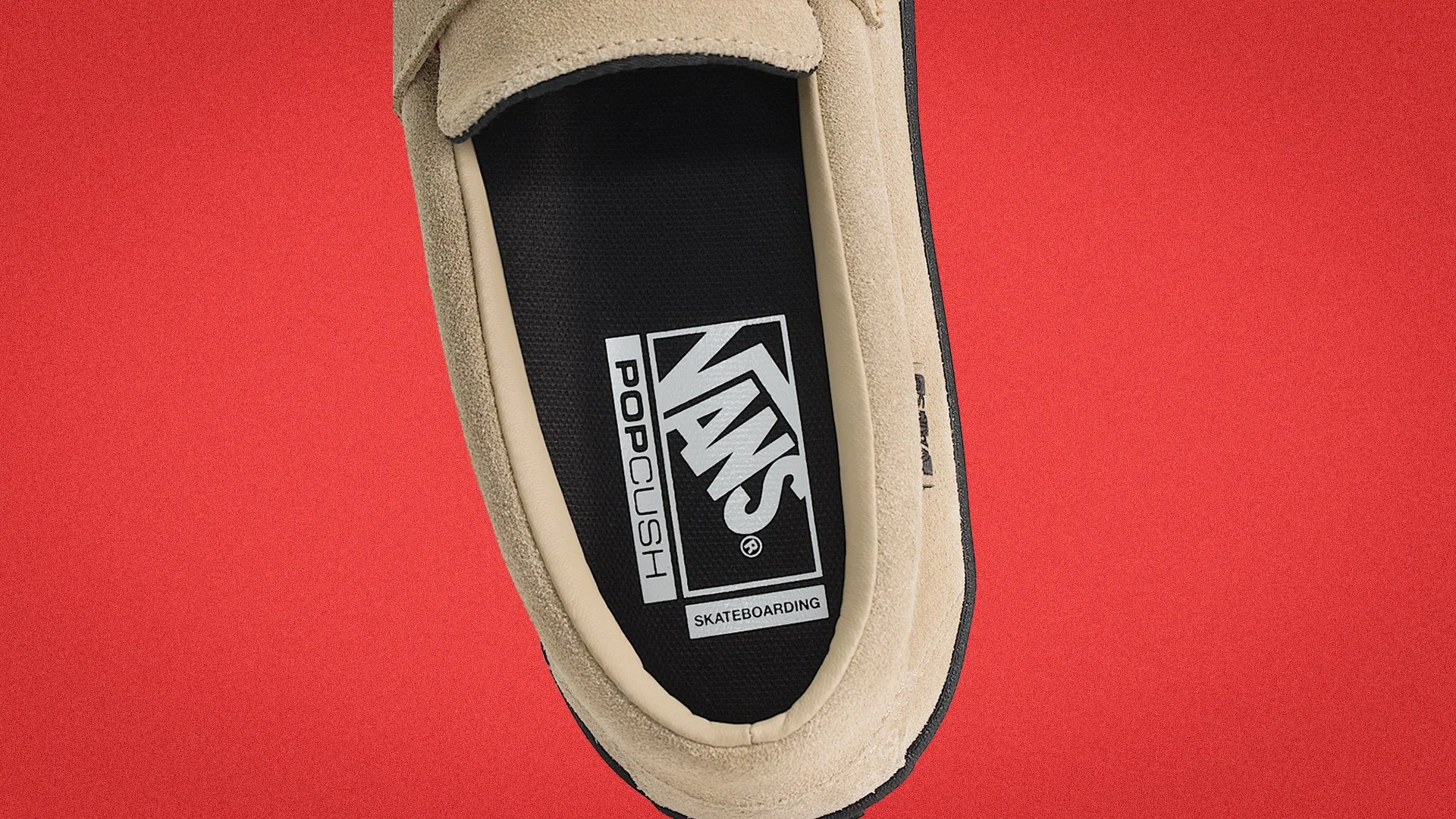 Close-up of a beige suede Vans shoe with black PopCush insole on a red background.