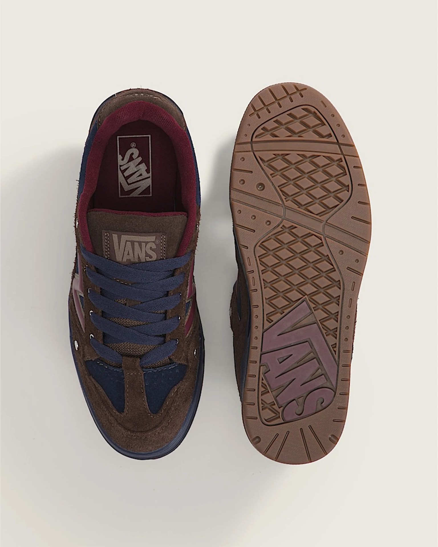 Pair of brown and navy Vans sneakers with blue laces, one showing top view and the other showing sole.
