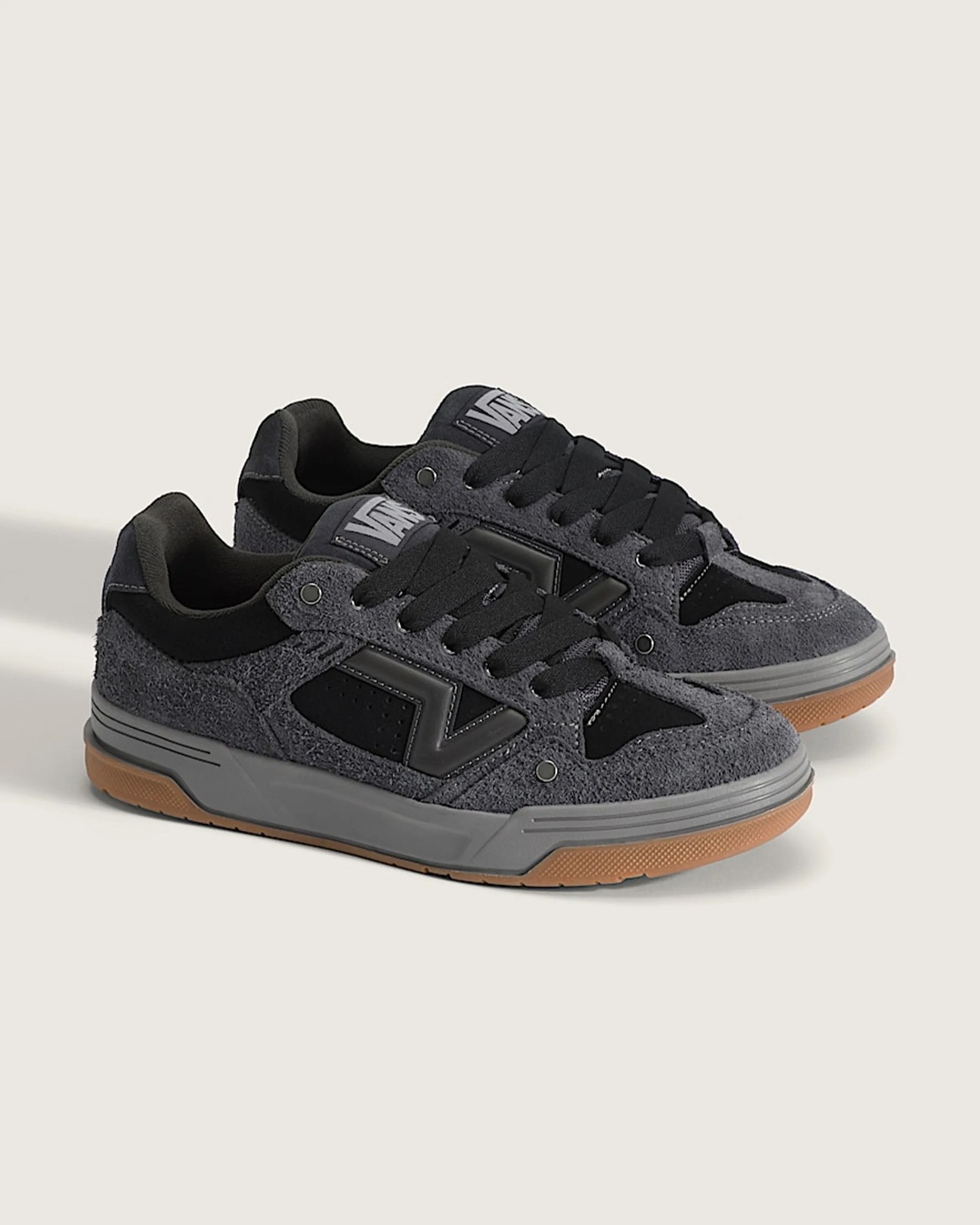 Pair of gray and black suede sneakers with gum rubber soles and black laces on a light background.