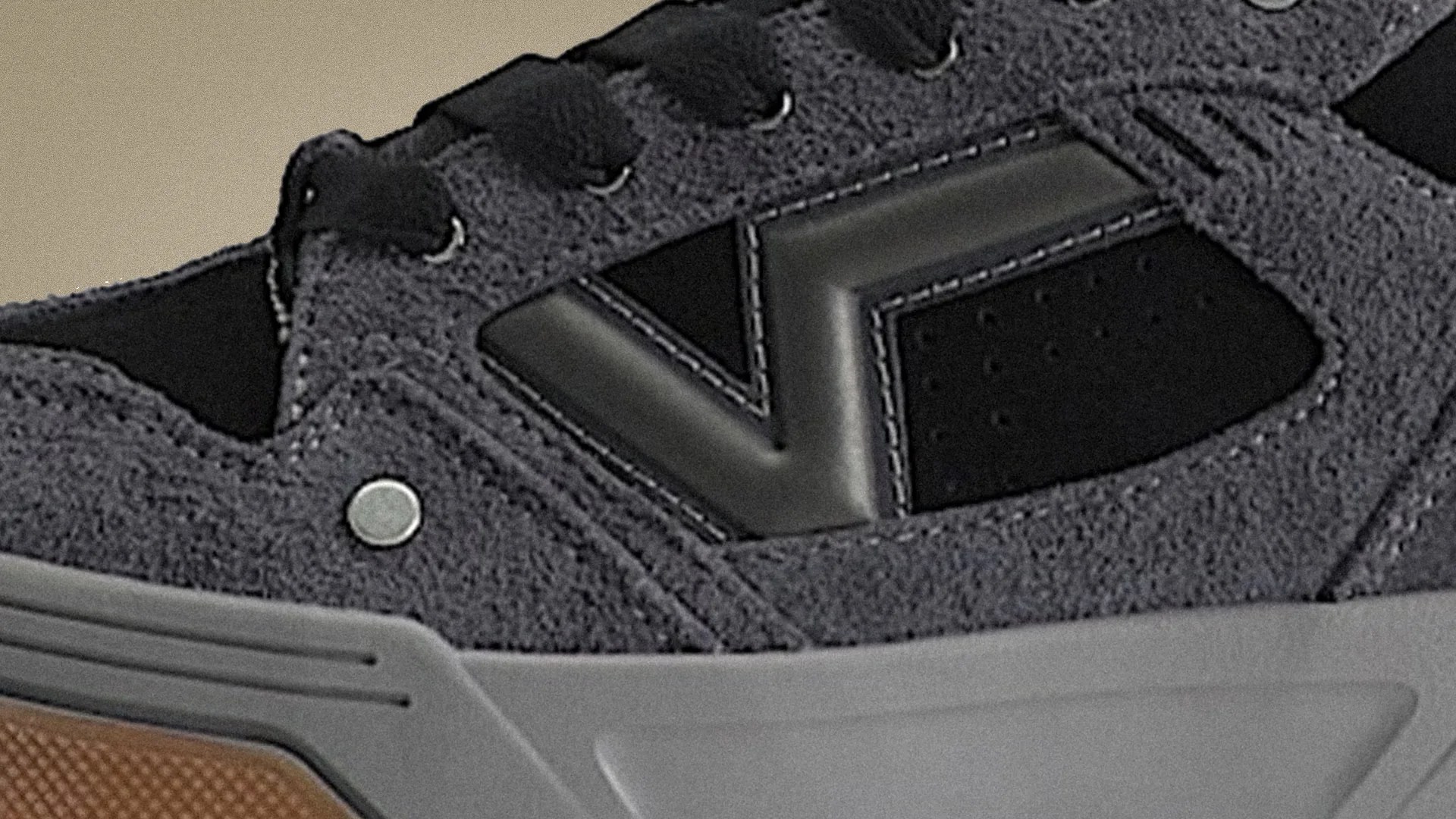 Close-up of a gray suede sneaker with black leather accents and a gray rubber sole.