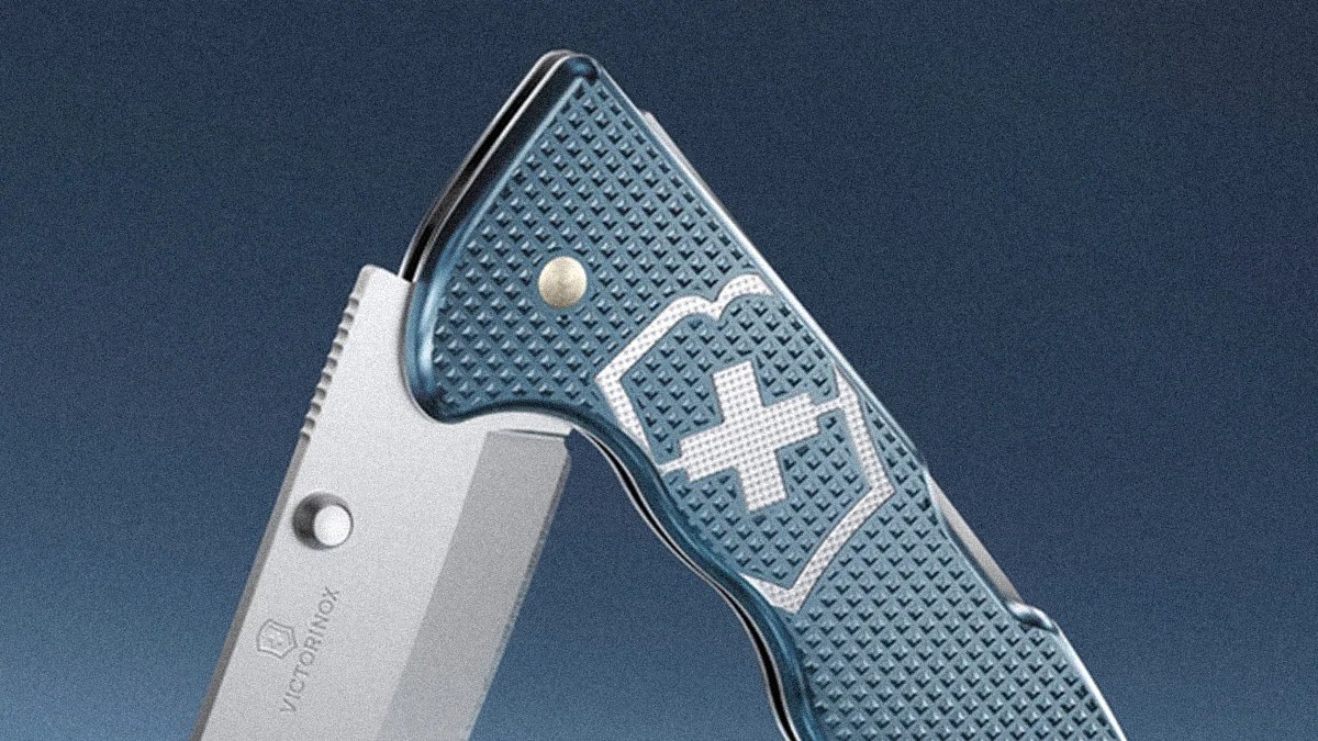 Close-up of a blue textured Victorinox Swiss Army knife handle with a white cross emblem and part of the stainless steel blade.